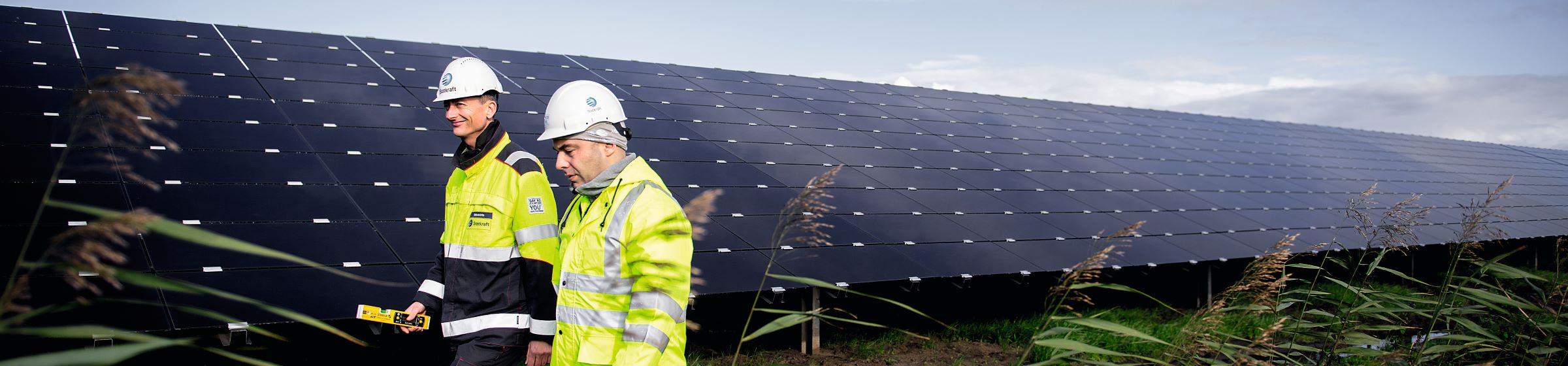 Zwei Statkraft-Arbeiter in Sicherheitskleidung vor einer großen Solaranlage