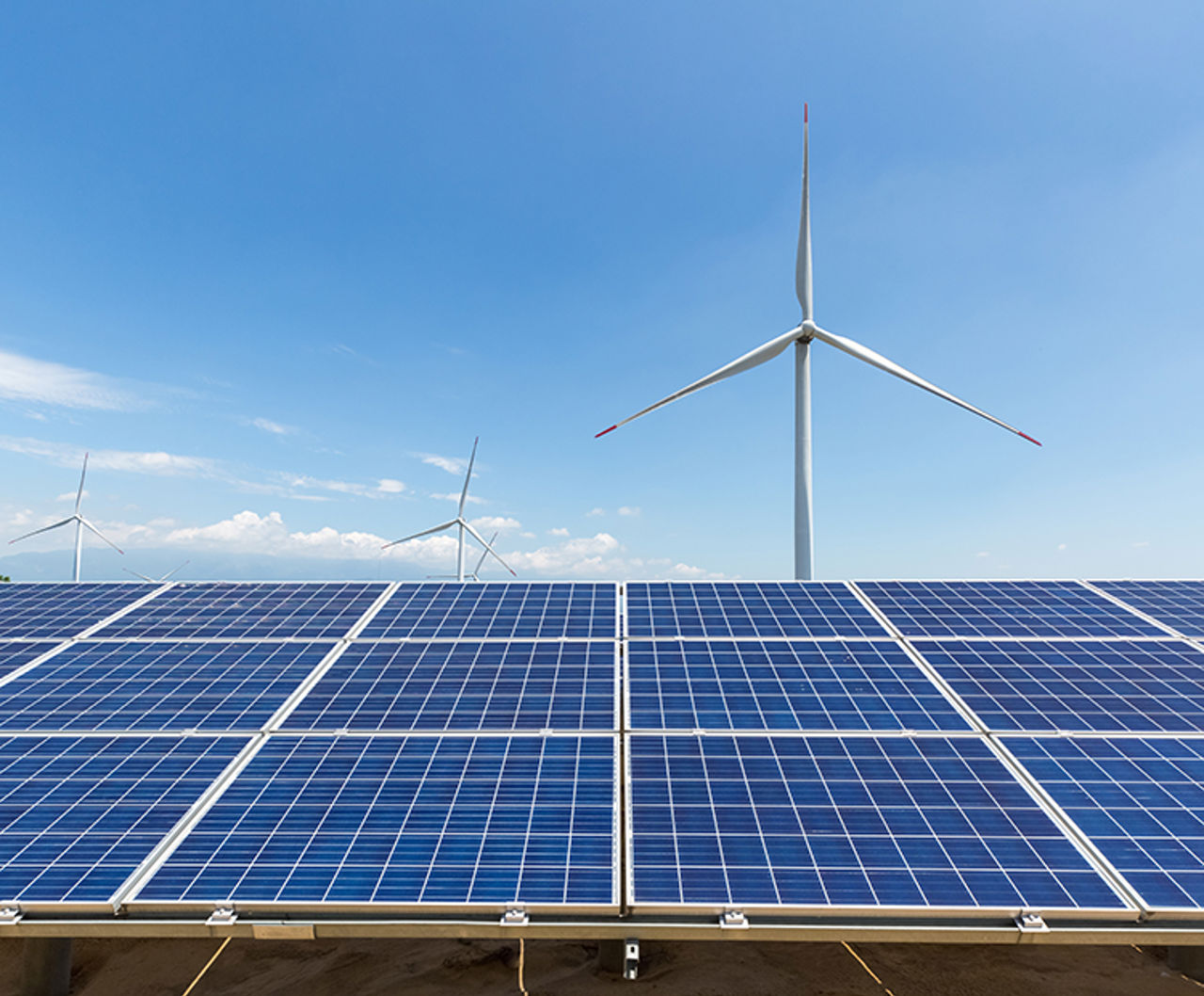 Windräder im Hintergrund und Solarpaneele im Vordergrund