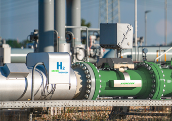Eine Pipeline für grünen Wasserstoff, im Hintergrund ein Industriegebiet